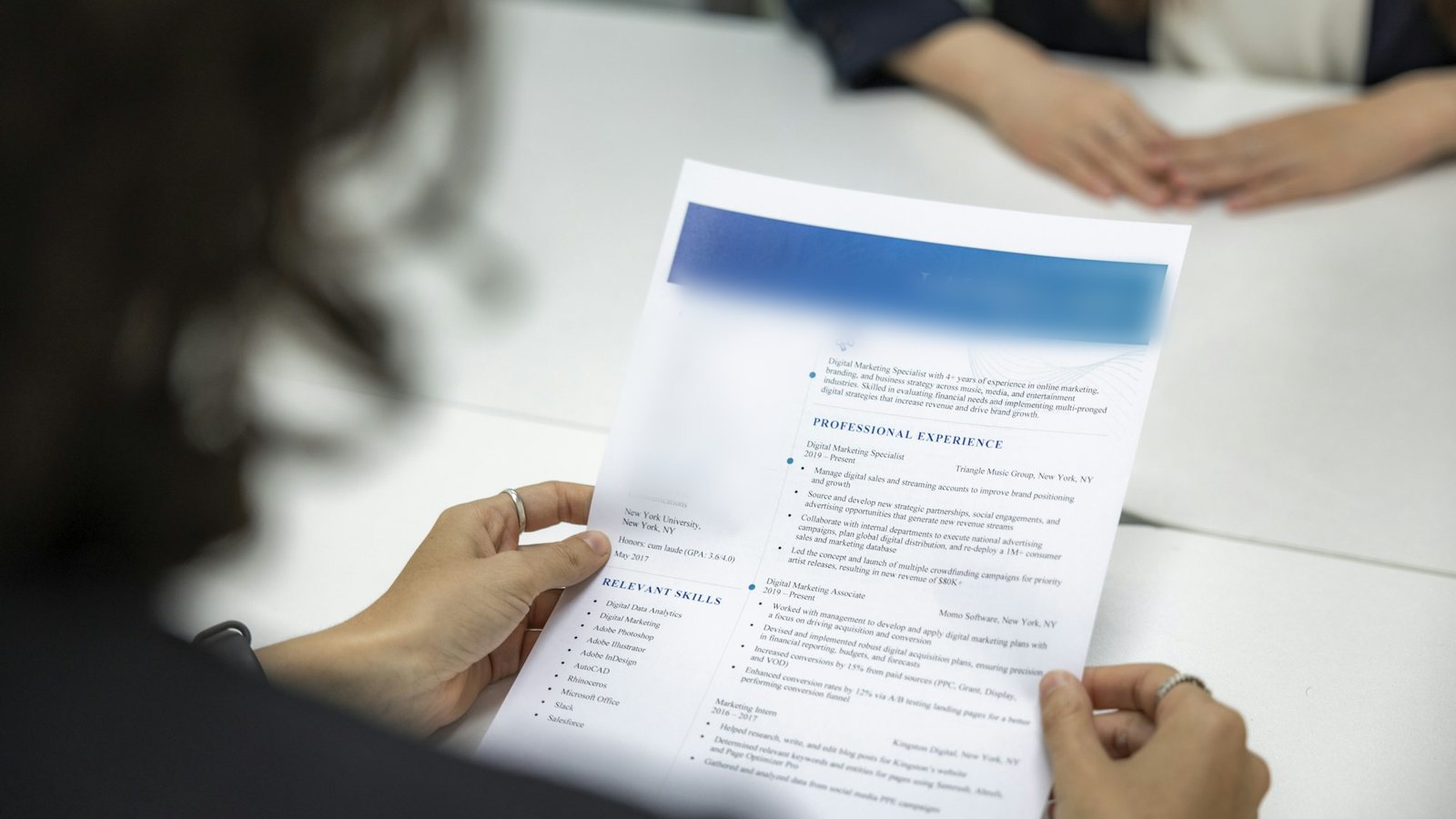 A person reviewing a printed resume across a table (illustrative photo).
